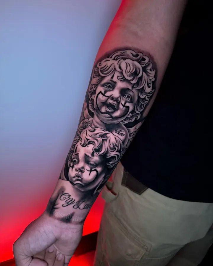 Black and grey tattoo by Dre: cherub faces, forearm