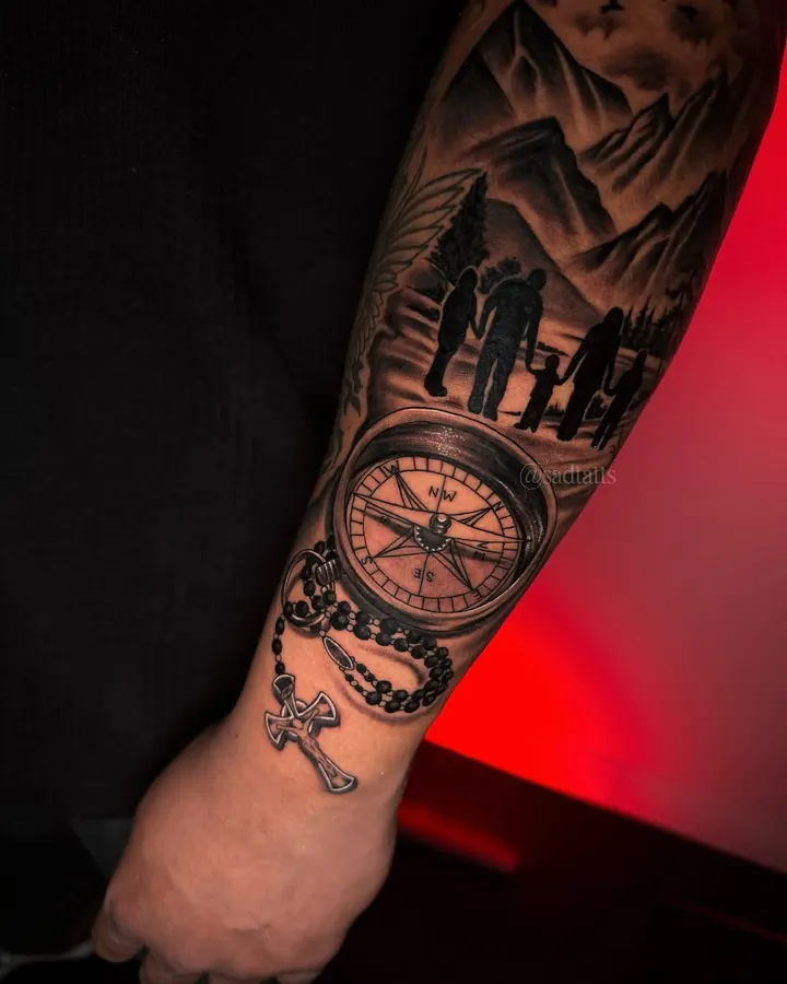 Black and grey tattoo by Dre: compass and family silhouette, forearm
