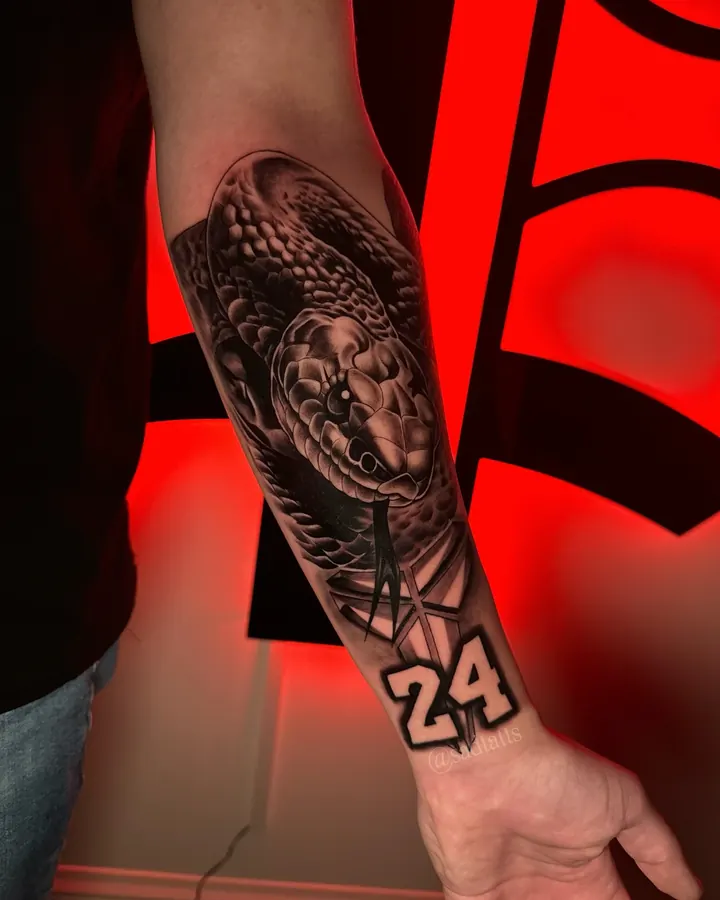 Black and grey tattoo by Dre: buddha and number 24, forearm