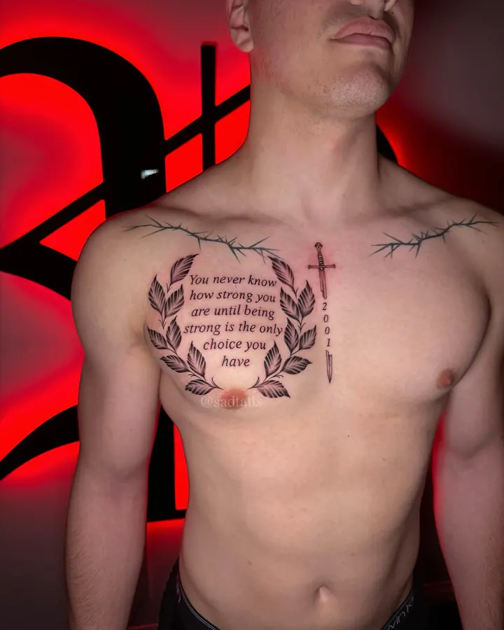 Black and grey tattoo by Dre: laurel script and cross, chest