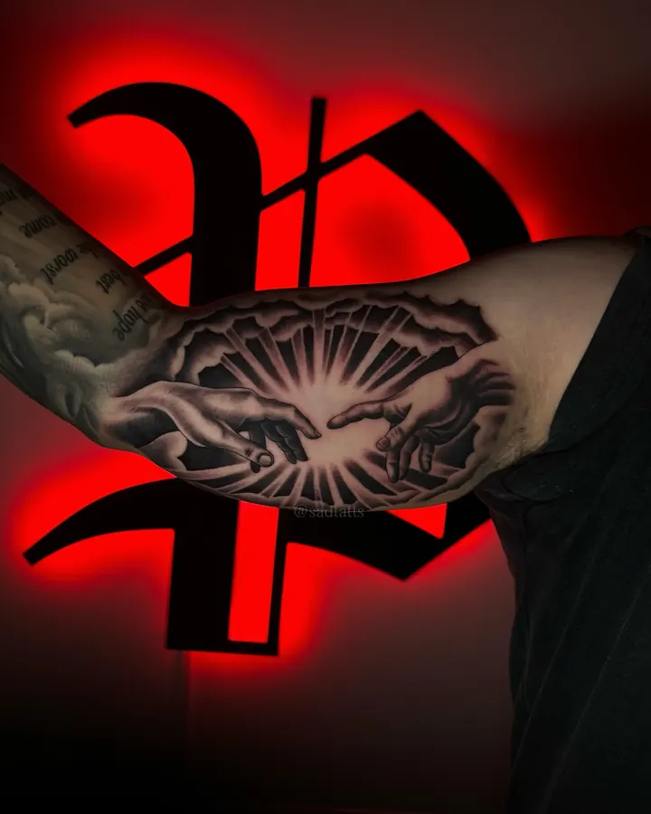Black and grey tattoo by Dre: hands and rays, upper arm