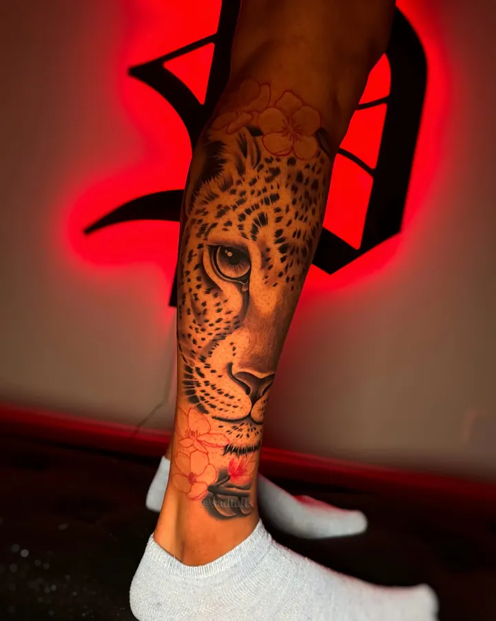 Black and grey tattoo by Dre: leopard face, calf